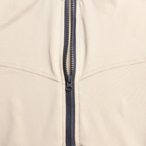 Detailed close-up of the high-quality dark gray metal zipper on beige ribbed fabric