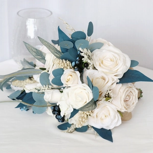 Cascade bridal bouquet with white roses, blue eucalyptus, and berries for wedding photos