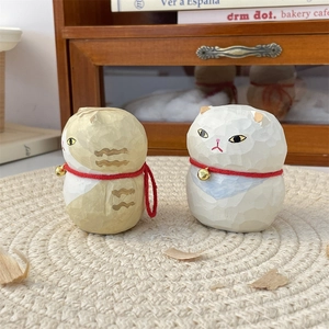 Detailed view of hand-carved wooden cat figurines with small bells on a woven mat