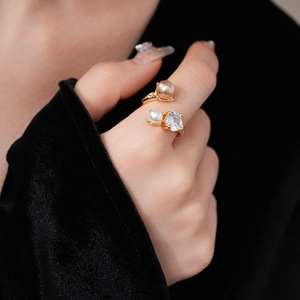 Detail of adjustable gold ring featuring white pearls and a brilliant round zircon stone