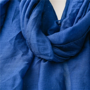 Close-up of blue cotton linen fabric texture with shiny silver metallic fringe detail