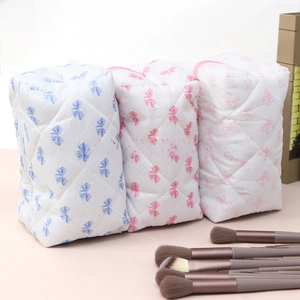 Quilted bow makeup bags in blue and pink with a set of makeup brushes in a neat layout