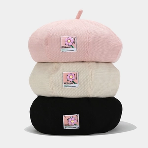Stack of pink, beige, and black vintage beret hats with floral patch for women