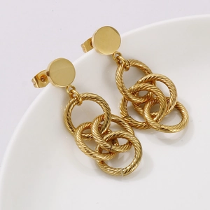 Vue macro de boucles d'oreilles dorées à pompons avec design poli à trois anneaux chaînés