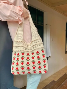 Detail of beige crochet tote bag featuring red strawberry knit patterns and wavy edges