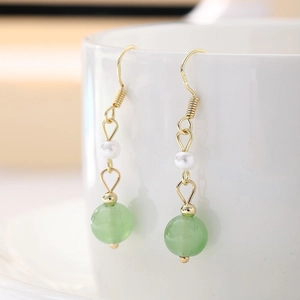 Detailed macro view of 925 silver gold-plated earrings with pearls and green jade beads