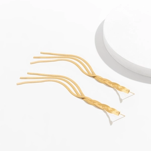 Macro detail of elegant golden snake chain tassel earrings on a white aesthetic background