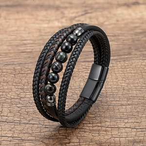 Detail of multi-layer men's bracelet with braided leather and dark glossy beads on wood