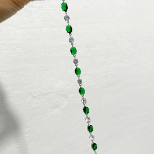 Détails macro des pierres d'émeraude ovales et zircons blancs sur un bracelet argenté