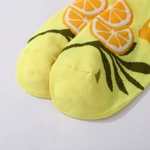 Detailed close-up of yellow cotton crew socks featuring bright orange citrus fruit patterns
