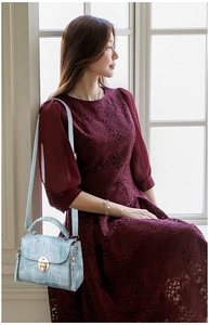 Detail of light blue textured handbag with golden circular twist lock and adjustable strap