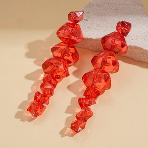 Close-up of red geometric acrylic earrings with faceted cut on a stone texture