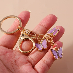 Detail of hand-held golden butterfly keychain with purple enamel charms and rhinestones