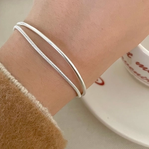 Close-up of a minimalist silver S925 bangle and snake chain bracelet set on a wrist