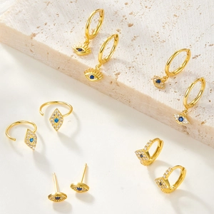 Detailed view of evil eye earrings in gold finish with blue stones and white crystals