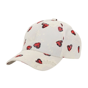 Detail of cream baseball cap featuring red graffiti heart pattern and textured fabric