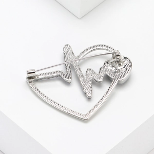 Detail of silver heart brooch with electrocardiogram line and sparkling rhinestones
