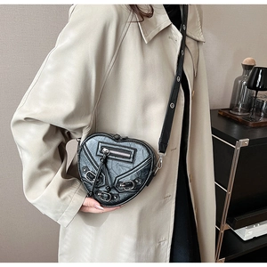 Détails d'un sac à bandoulière noir en forme de cœur avec rivets et éléments de style biker