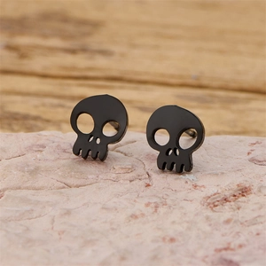 Close-up of black skull stud earrings made of stainless steel on stone background