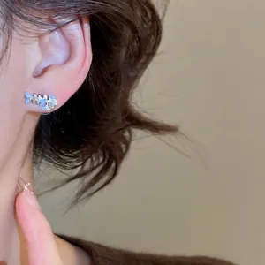 Silver fishbone cat earrings with pearlescent inlay on a model's ear in minimalist style