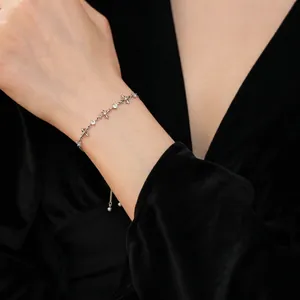 Silver thin chain bracelet with zircon cross star elements on a black background