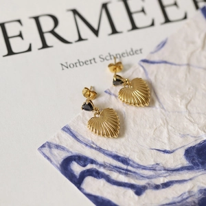 Macro shot of 18K gold plated heart earrings with black zircon and radiant metal texture