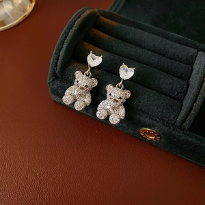 Détail macro de boucles d'oreilles cœur en zircon avec pendentifs d'ours scintillants