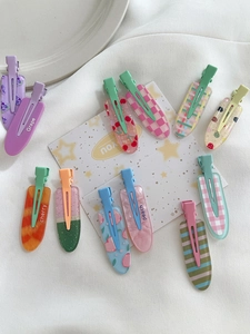 Flat lay of colorful oval candy-colored hair clips with fruit patterns on white fabric