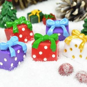 Macro shot of miniature resin Christmas gift boxes among faux snow and tiny trees