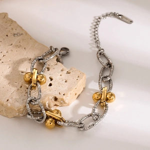 Detail of two-tone stainless steel link chain bracelet with gold beads on stone