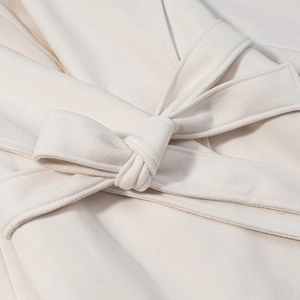 Detailed close-up of a cream-white wool coat featuring a stylish knotted waist belt