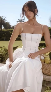 Close-up of white corset-style strap dress featuring delicate lace stitching and flared skirt