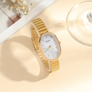 Elegant gold oval quartz watch for women with minimalist white dial on beige background