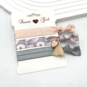 Detailed view of three elastic hair ties with floral patterns and love heart charms