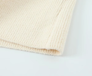 Détail macro du tissu en maille crème montrant la texture côtelée et la finition soignée