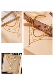 Detail of layered gold-plated butterfly necklace with white shell pendant and multi-tier chains