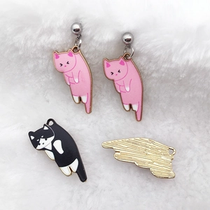 Detailed view of colorful cat-shaped enamel pendants on soft white plush background