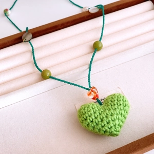 Détail de pendentif cœur au crochet fait main avec perles colorées sur plateau velours