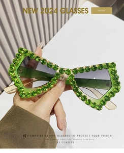 Detail of oversized butterfly sunglasses with green rhinestones and gradient lenses