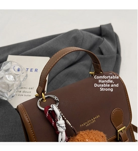 Close-up of brown PU leather handbag handle with a stylish woven rope tassel and pompom