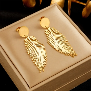 Fashionable long hollow feather pendant earrings in gold finish on a jewelry box