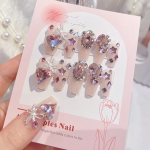 Detail of handmade press-on nails with 3D bows, heart crystals, and glitter decoration