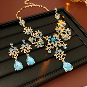 Detailed close-up of gold flower jewelry set with blue zircon teardrop stones