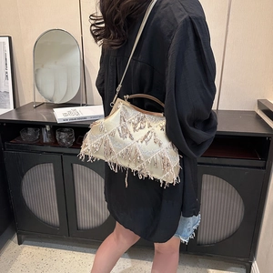 Detail of a vintage golden fringe evening bag with a metal chain strap on a model