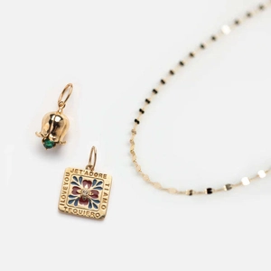 Detailed macro view of gold plated necklace with engraved I Love You square charm and green gem