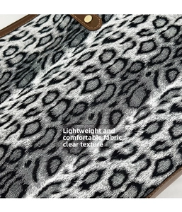 Détail du cabas en toile léopard avec bordure en cuir marron et bouton-pression doré