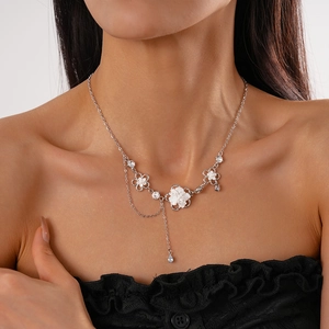 Dettaglio della collana elegante con fiori e nappe con perle indossata sul collo
