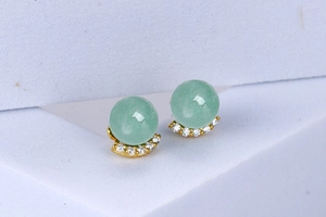 Macro shot of silver crescent earrings featuring green aventurine stones and white zircons