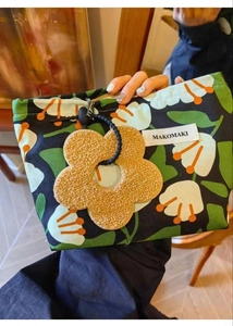 Detailed close-up of tropical floral canvas cosmetic bag with brown plush flower keychain