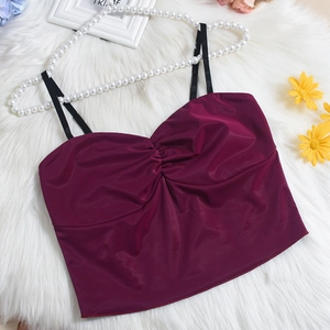 Détail du crop top en satin bordeaux avec bretelles noires et buste plissé sur fourrure